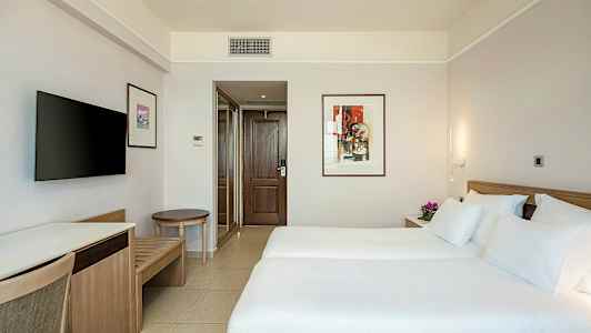 Hotellrum med två enkelsängar, dekorativt konstverk på vägg, och TV. (AI-genererad text)