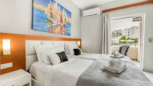 Ett hotellrum med två sängar, konstverk ovanför sängarna, och en balkong med utsikt. (AI-genererad text)