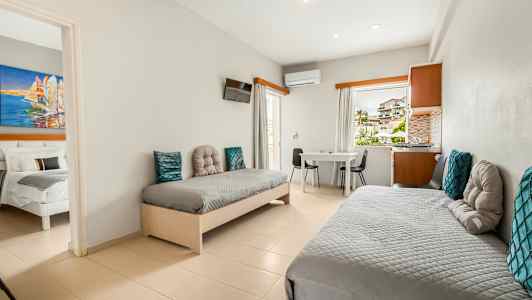 Ett hotellrum med två enkelsängar, ett bord och stolar, samt utsikt genom fönstret. (AI-genererad text)