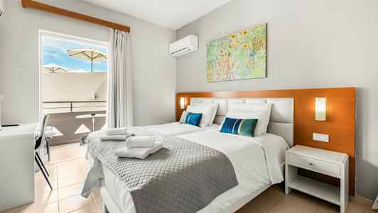 Bild av ett hotellrum med två sängar, en balkong med parasoller och tavla på väggen. (AI-genererad text)