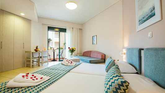 Hotellrum med två sängar, sittgrupp och utgång till balkong. (AI-genererad text)