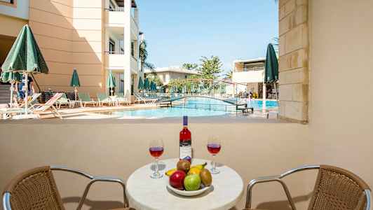 Bilden visar ett bord med frukt och vin framför en swimmingpool och en byggnad. (AI-genererad text)