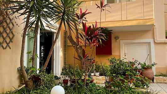 Exteriör av ett hus med grönskande trädgård framför. (AI-genererad text)