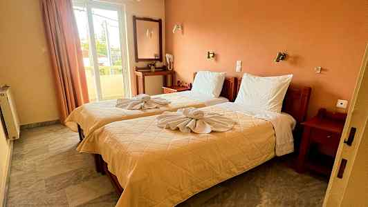 Ett hotellrum med två enkelsängar, dekorerade med vikta handdukar. (AI-genererad text)