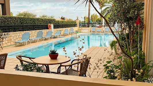 Bild av en utomhuspool med solstolar och bord med en blomkruka. (AI-genererad text)