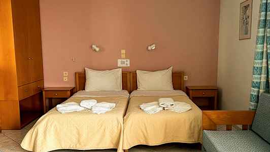 Ett hotellrum med två enkelsängar, nattduksbord, och hopvikta handdukar på sängarna. (AI-genererad text)