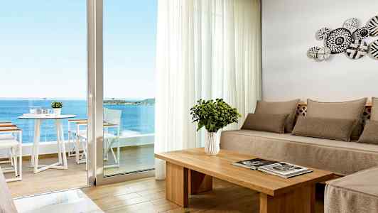 Modernt möblerat rum med havsutsikt genom en stor fönsterdörr. (AI-genererad text)