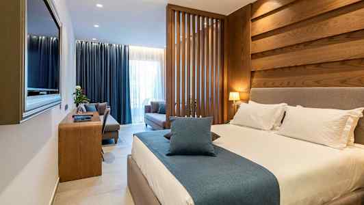 Ett hotellrum med en stor säng, sittområde och träpaneler. (AI-genererad text)