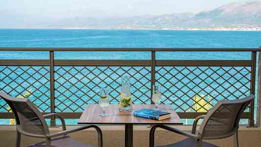 Två stolar vid ett bord med en karaff och två glas, med utsikt över havet. (AI-genererad text)