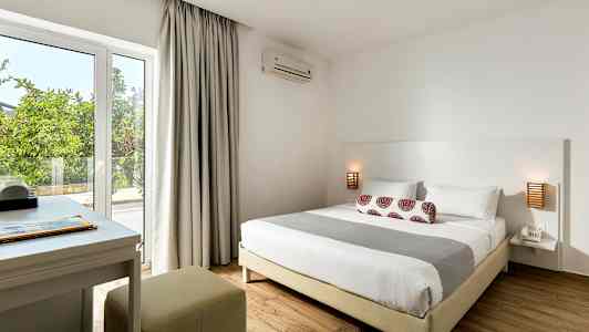 Ett sovrum med en dubbelsäng, sängbord och skrivbord nära fönstret. (AI-genererad text)