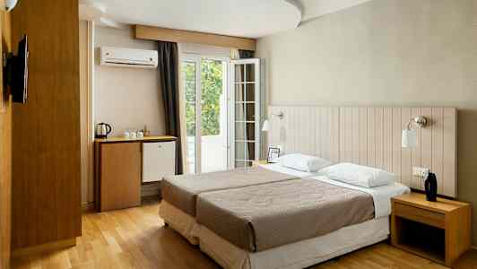 Ett hotellrum med två enkelsängar, skrivbord, minibarkyl och fransk balkong. (AI-genererad text)