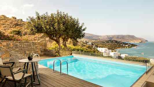 En pool med utsikt över havet och en sluttning med hus. (AI-genererad text)