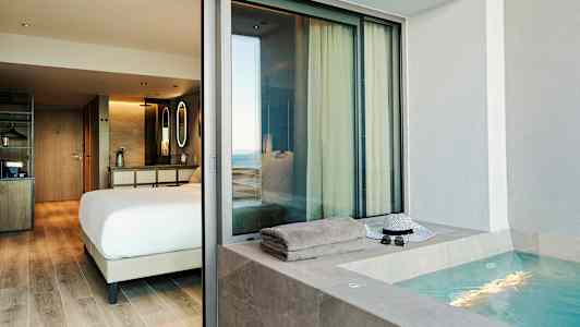 En hotellsvit med ett sovrum och en jacuzzi utomhus. (AI-genererad text)