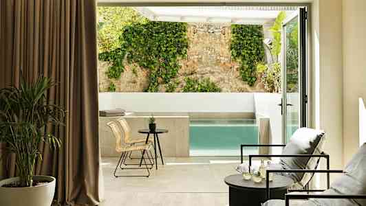 Modernt rum med sittgrupp och utsikt över privat pool och vägg med klätterväxt. (AI-genererad text)