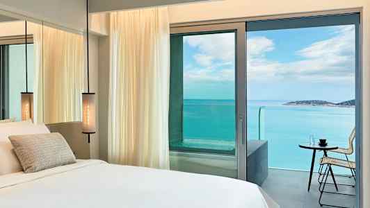 Hotellrum med havsutsikt genom balkongdörren. (AI-genererad text)