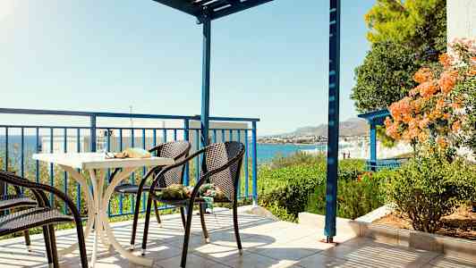 En terrass med stolar och ett bord, havsutsikt och grönska. (AI-genererad text)
