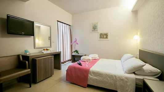 Hotellrum med dubbelsäng, sängbord och skrivbord. (AI-genererad text)