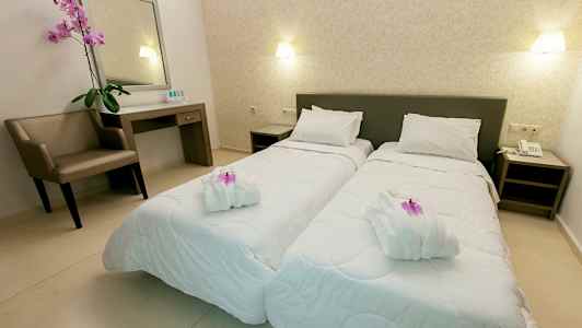 Två enkelsängar i ett välorganiserat hotellrum med en stol, ett skrivbord och dekorativa element. (AI-genererad text)