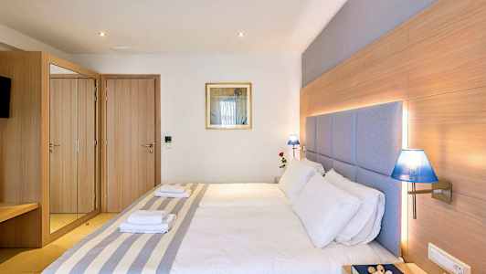 Ett hotellrum med en dubbelsäng, trädetaljer, blå lampor och ett spegelskåp. (AI-genererad text)