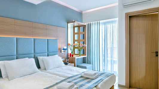 Ett hotellrum med en dubbelsäng med vita sängkläder, träpaneler och blåa detaljer. (AI-genererad text)