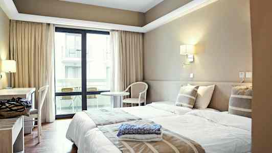 Hotellrum med två enkelsängar, skrivbord och balkong. (AI-genererad text)