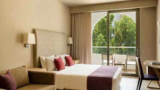 Hotellrum med dubbelsäng, soffa och utgång till balkong. (AI-genererad text)