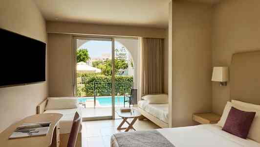 Ett hotellrum med en dubbelsäng, en skrivhörna, och en extra säng. Utanför syns en terrass och en pool. (AI-genererad text)