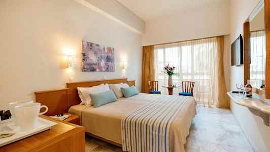 Hotellrum med en dubbelsäng, två stolar och ett bord vid fönstret. (AI-genererad text)