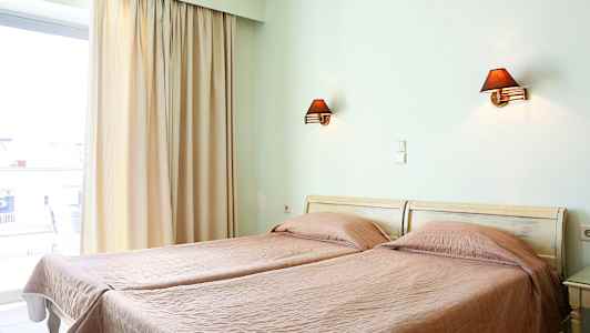 Två enkelsängar med rosa täcken i ett rum med en fönsteröppning och vägglampor. (AI-genererad text)