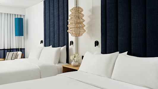 Två bäddar med vita sängkläder i ett hotellrum. (AI-genererad text)