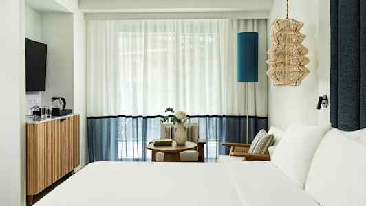 Hotellrum med dubbelsäng, sittmöbler och TV. (AI-genererad text)