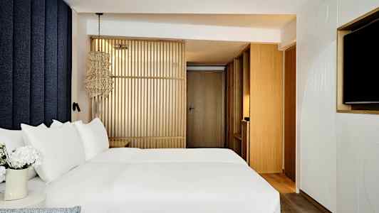 Bild av ett modernt hotellrum med en säng med vita lakan och trädetaljer. (AI-genererad text)