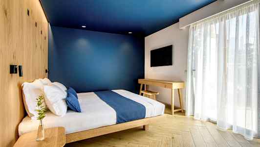 Ett modernt hotellrum med blå väggar, en säng med blå överkast och träinredning. (AI-genererad text)