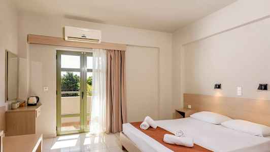 Ett hotellrum med en dubbelsäng, två nattduksbord och en uteplats med ljusa gardiner. (AI-genererad text)