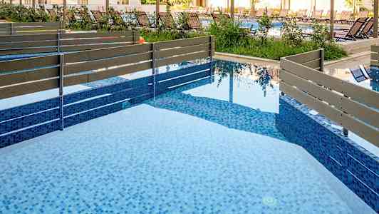 Bild av en modern pool med blå mosaik och trästaket. (AI-genererad text)