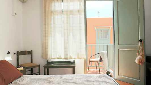 Ett sovrum med öppen dörr till en balkong. (AI-genererad text)