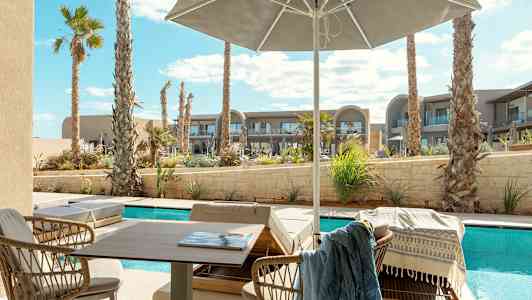 Solterrass med utsikt över pool och palmer, med utemöbler under parasoll. (AI-genererad text)