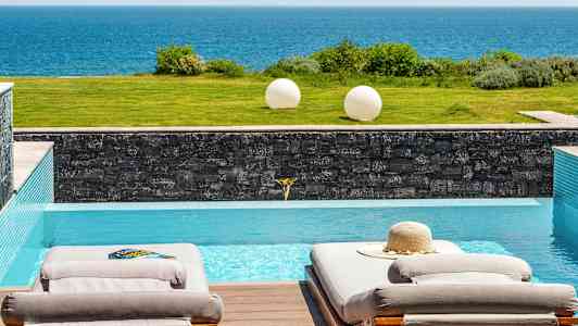 Två solstolar vid en pool med utsikt över havet. (AI-genererad text)