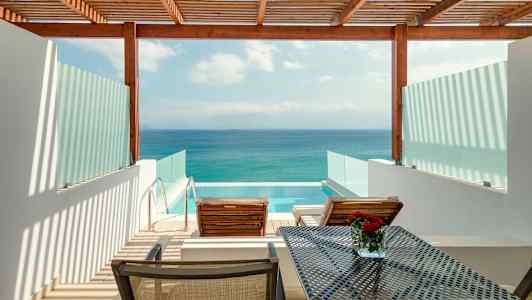 Utsikt över en terrass med två solstolar, ett bord och en privat pool, med havet i bakgrunden. (AI-genererad text)