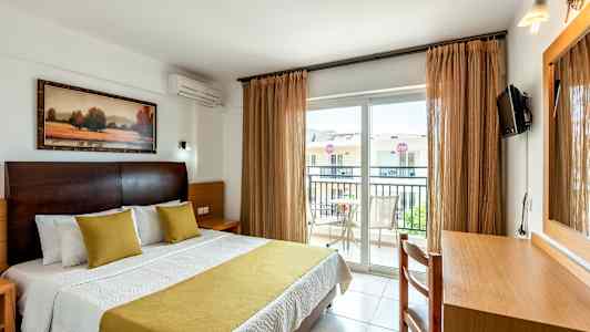 Interiör av hotellrum med en säng, skrivbord och balkong. (AI-genererad text)