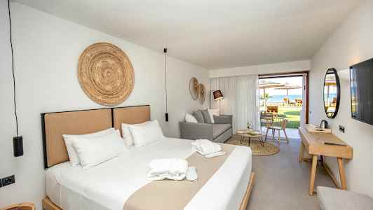 En hotellsvit med en dubbelsäng, sittplats och utgång till en möblerad uteplats. (AI-genererad text)