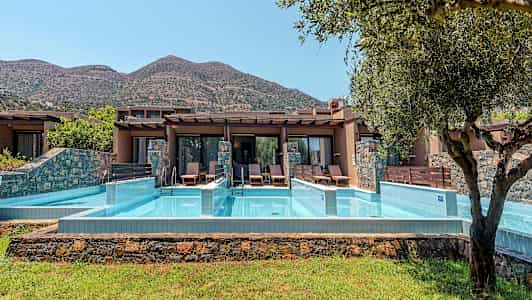 Privat poolområden framför semesterbostäder med berg i bakgrunden. (AI-genererad text)