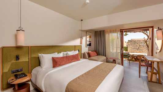 Ett modernt hotellrum med en stor säng, bekväma möbler och en uteplats. (AI-genererad text)