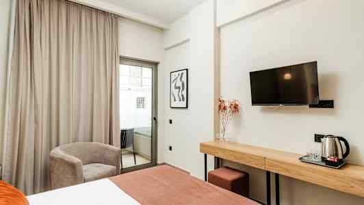 Hotellrum med säng, skrivbord, stol och balkong. (AI-genererad text)