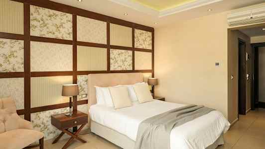 Ett hotellrum med en säng, en stol och två nattduksbord med lampor. (AI-genererad text)