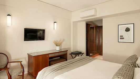 Bild av ett hotellrum med en säng, en TV på väggen, ett skrivbord och en fåtölj. (AI-genererad text)