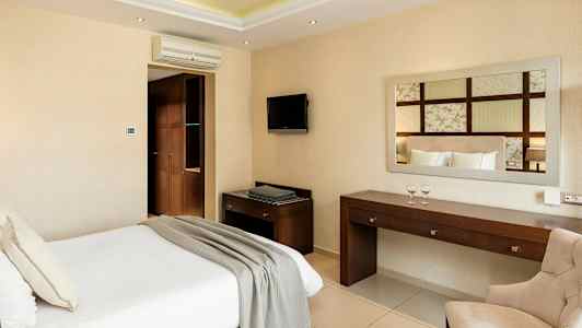 Ett hotellrum med en säng, skrivbord, stol och väggtv. (AI-genererad text)