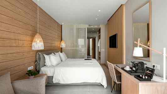 Ett ljus och modernt hotellrum med en stor dubbelsäng, en skrivbordsplats och en dekorativ marmorpanel på väggen. (AI-genererad text)