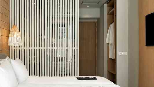 Hotellrum med en säng, en trävägg och en garderob. (AI-genererad text)