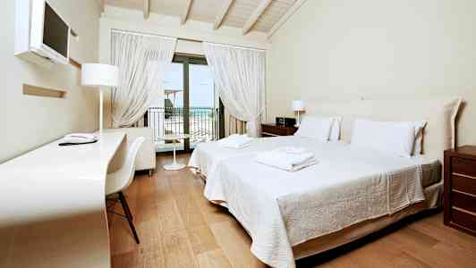 Ett hotellrum med två enkelsängar, ett skrivbord och en balkong med utsikt. (AI-genererad text)